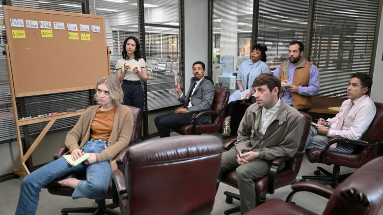 The Paper's staff sit in a drab conference room with looks of circumspection, shock, confusion, and boredom.