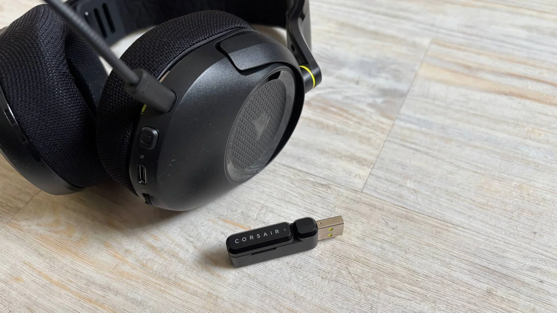 Corsair HS35 v3 headset earcup and dongle and headset on a white hardwood floor