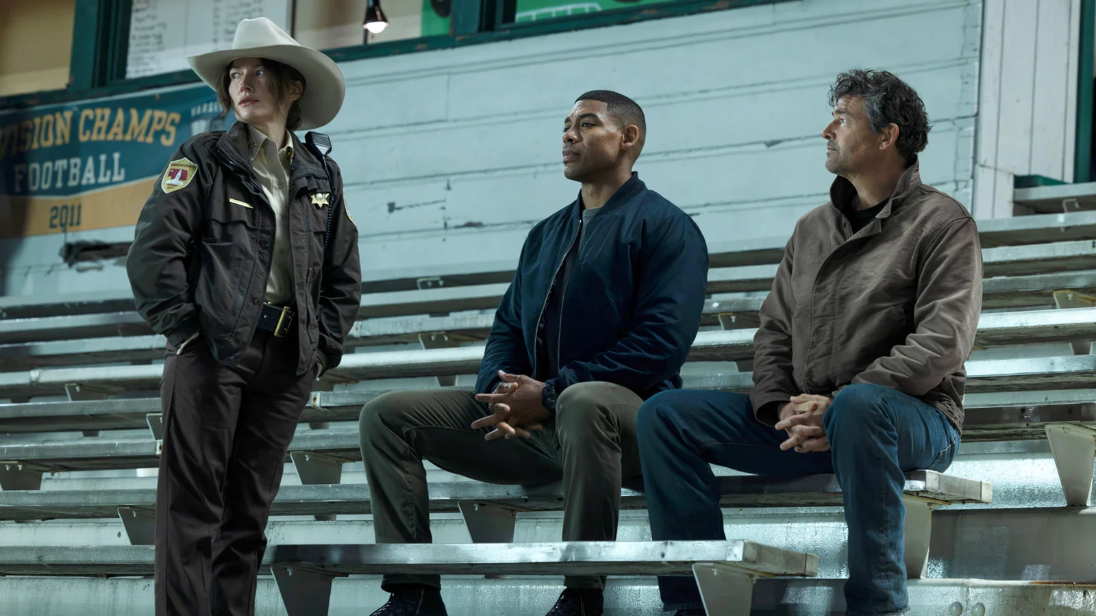 John Stewart and Hal Jordan sitting down and looking at a standing Sheriff Kelly in Lanterns