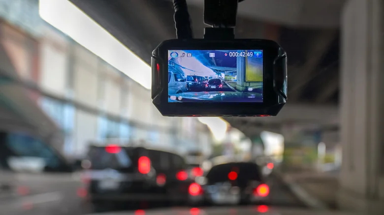 A dash cam mounted in a car with blurred cars in front of the vehicle.