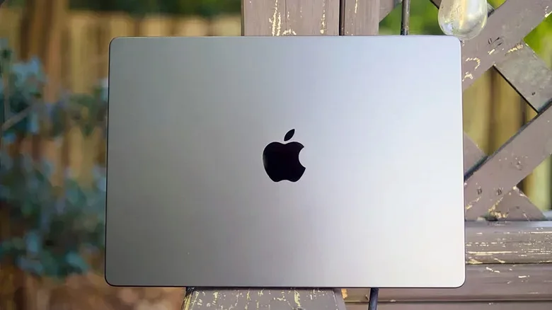 The back of a MacBook Pro sitting on an outdoor bench.