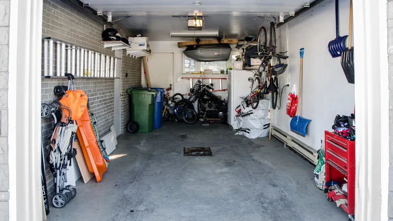 Garage with no car, full of boxes, tools, and other storage.
