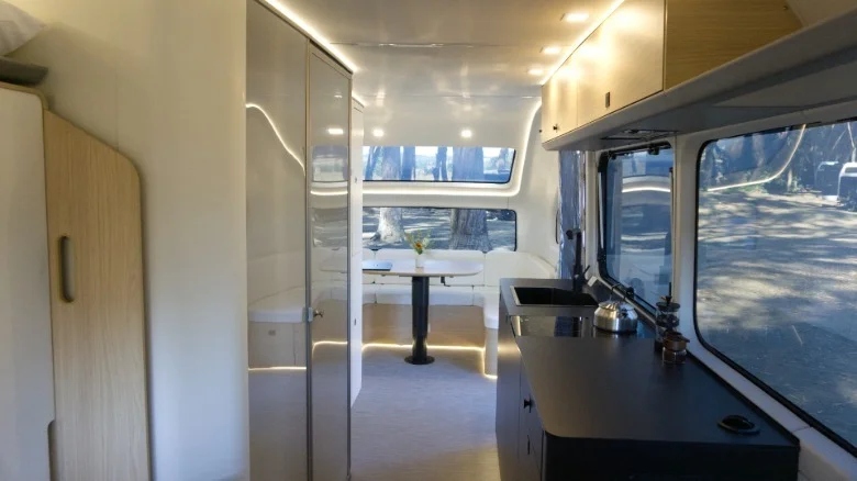 The inside of a Flow trailer with a sink and countertop on the right and dinette in the back.